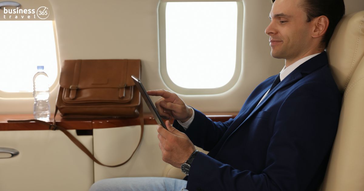 man sitting in business class flight cabin and using ipad